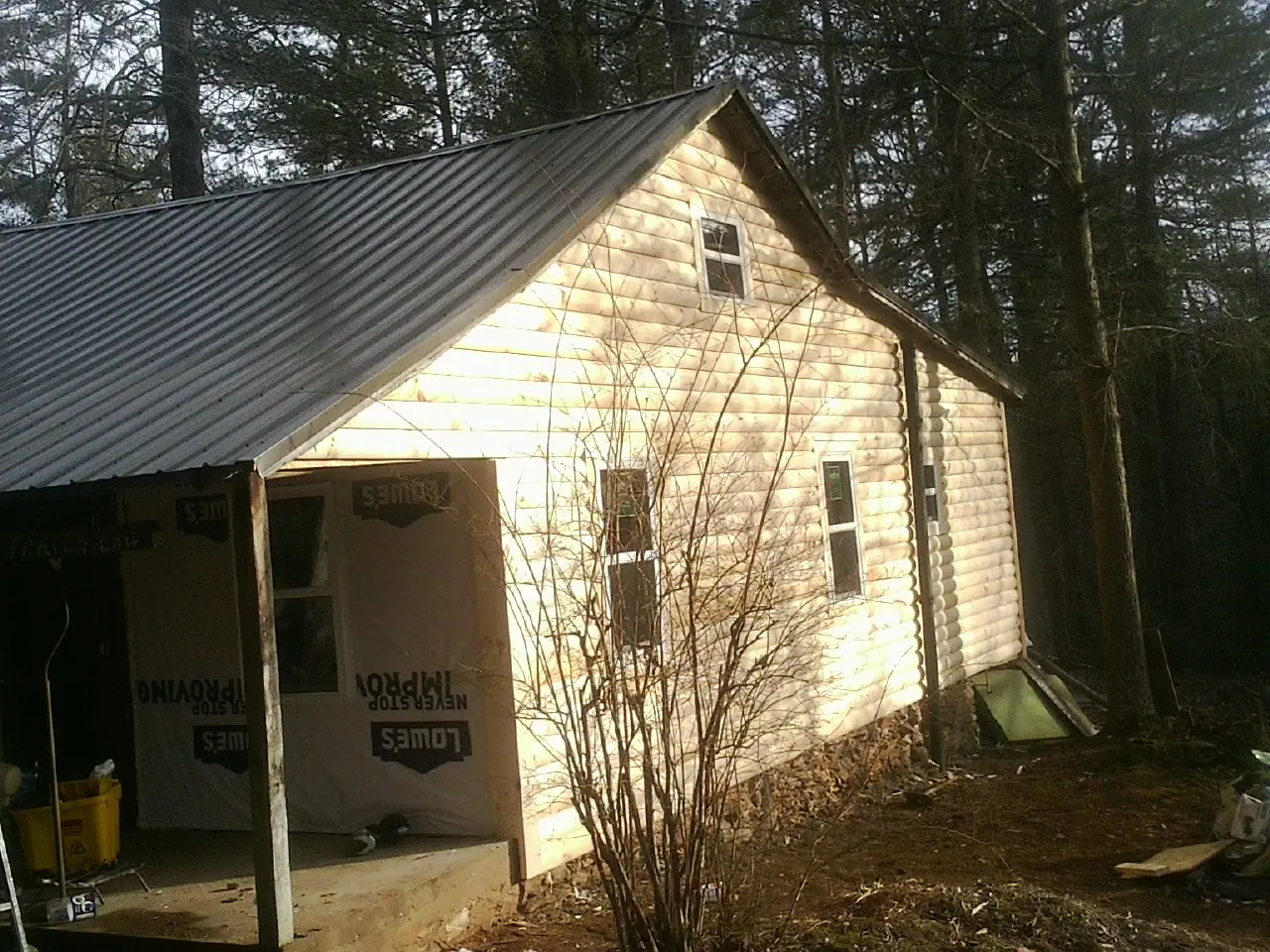 Log siding gable end under a dark metal roof edge in Wellsburg