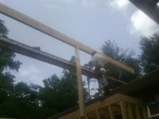 Carpenter setting a ridge beam over a new addition frame — Ice Dam Removal by Roofing Brothers in Wellsburg
