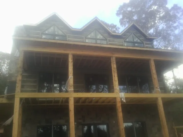 Dormers and porch framing on a large log home under construction — Roof Coating work by our crew in Wellsburg