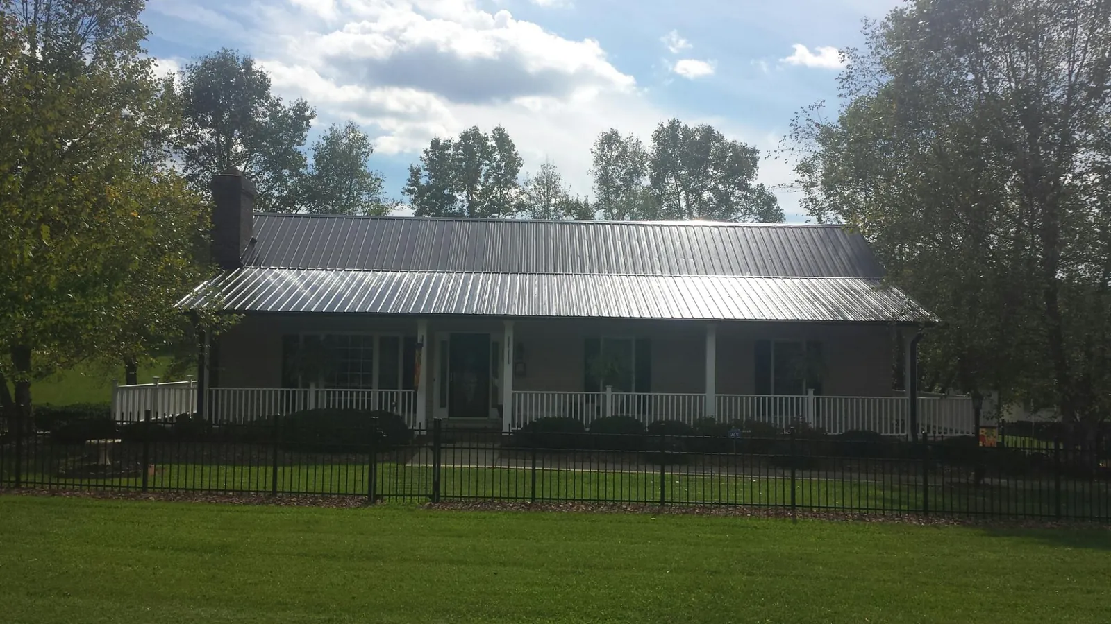 Gray metal roof on a brick ranch with a full width front porch — Gutter Guard Installation work by our crew in Wellsburg