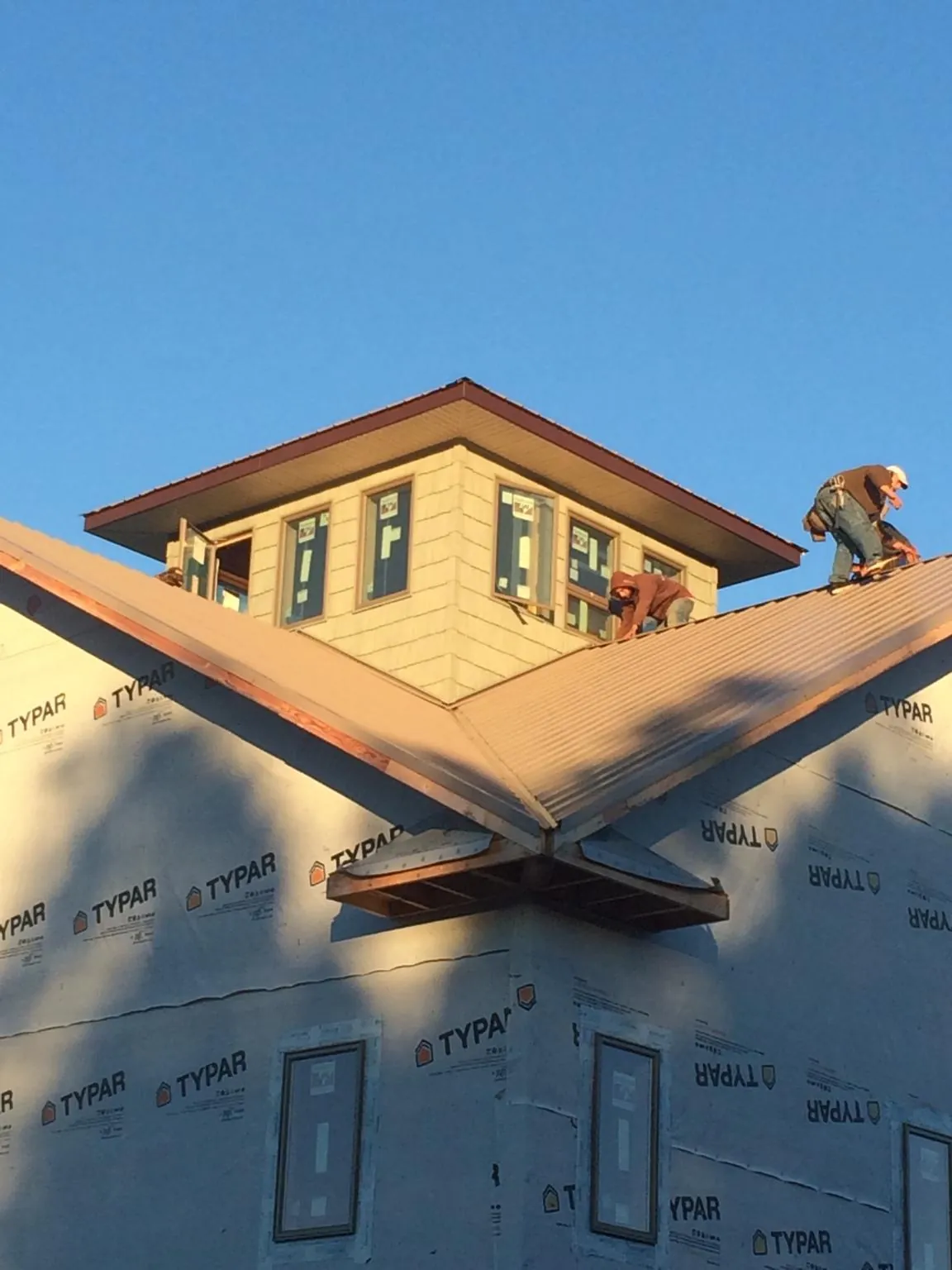 Roofers working around a rooftop cupola on a new metal roof at sunset — Roof Waterproofing in Wellsburg by Roofing Brothers